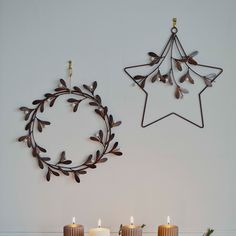 three candles are lit in front of a christmas wreath and star hanging on the wall