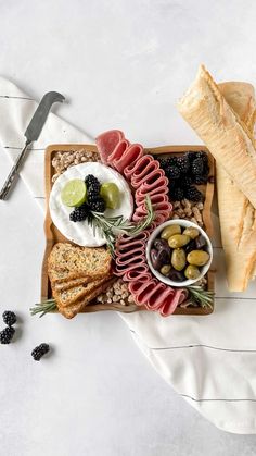 an assortment of meats, bread and olives on a platter