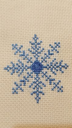 a cross stitch snowflake is shown in blue