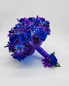 a bridal bouquet with purple flowers and blue ribbon on the end is shown in front of a white background