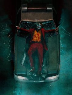 the joker is laying down on top of a car with his arms out and legs spread wide