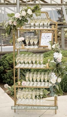 a wine rack filled with champagne glasses and greenery next to a sign that says, who doesn't love a pre - ceremony drink during this wedding?