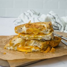 two sandwiches stacked on top of each other next to a fork and napkin with a white towel in the background