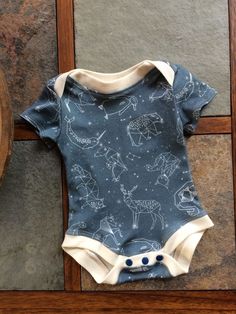 a baby bodysuit sitting on top of a wooden floor