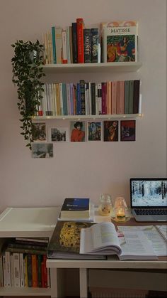 a laptop computer sitting on top of a desk next to a book shelf filled with books