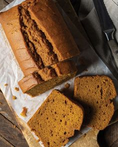 sliced loaf of pumpkin bread sitting on top of a cutting board next to two slices