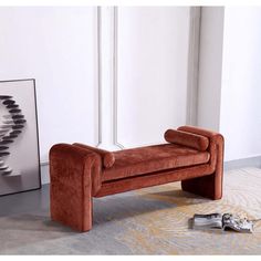 an orange velvet bench sitting in front of a white wall