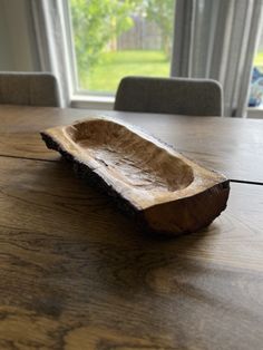 a wooden boat sitting on top of a wooden table next to a window in a room