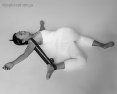 a woman laying on the ground with her arms out and legs crossed, wearing a white bodysuit