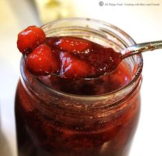 a spoon full of strawberry jam on top of a jar