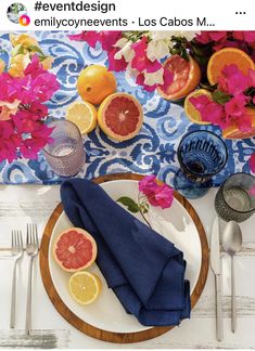 a plate with grapefruits, oranges and lemons on it next to silverware