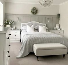 a bedroom with a bed, dressers and white furniture