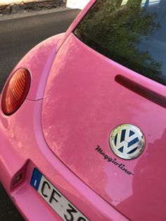 a pink vw beetle parked on the side of the road