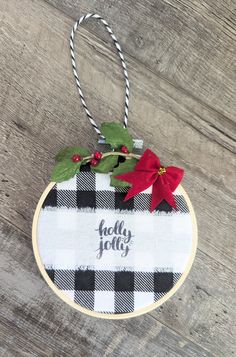 a christmas ornament hanging on a wooden wall with holly and poinsettis