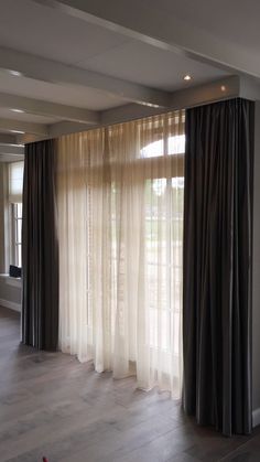 an empty living room with large windows and curtains