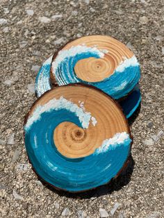 two pieces of wood that have been painted with blue and white waves on them, sitting on the ground