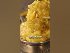 a metal bowl filled with yellow food on top of a table next to a fork