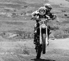 a man riding on the back of a motorcycle down a dirt road