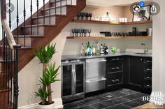 a kitchen with stainless steel appliances and black tile flooring next to a stair case