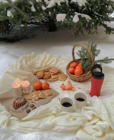 two cups of coffee sit on a blanket next to cookies and oranges