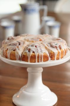 a bundt cake with icing sitting on top of a white plate and wooden table