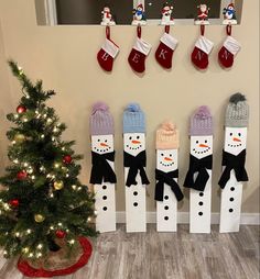 christmas stockings and snowmen are hanging on the wall next to a small christmas tree