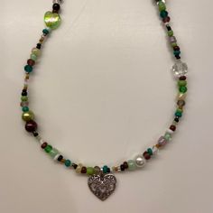 a necklace with a heart shaped pendant and multicolored glass beads on a white background