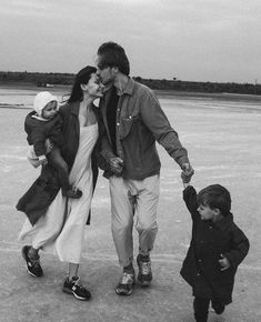 a black and white photo of a man, woman and two children walking on an airport tarmac