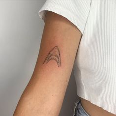 a woman's arm with a shark tattoo on the left side of her arm