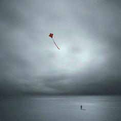 a person flying a kite in the middle of an ocean on a gloomy day