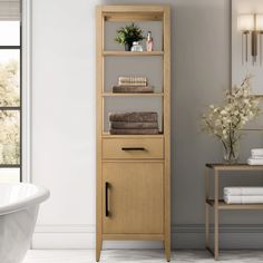 a white bath tub sitting next to a tall wooden shelf with towels on top of it