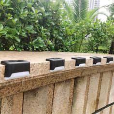 a row of black soap dispensers sitting on top of a stone wall