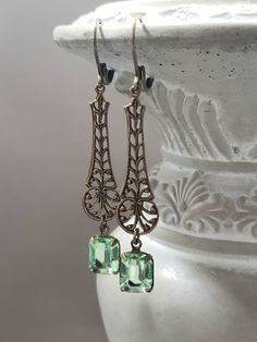 Textured Front, Hollow Back These 1920s inspired earrings feature Deco style antiqued brass connectors and peridot green vintage glass beads. I love the intricate details and lacy look of the long filigree connectors. They are lightweight yet sturdy, and extremely comfortable to wear. These long dangle earrings measure 2 1/2 inches long and hang from brass lever back ear wires. Create an elegant 1920s flapper look with these vintage style dangles. ABOUT THIS COLLECTION The sophisticated style of Elegant Brass Earrings With Antique Finish, Antique Brass Earrings With Vintage Charm, Antique Metal Earrings With Vintage Charm, Vintage Bronze Filigree Earrings, Victorian Brass Earrings With Vintage Charm, Vintage Brass Earrings For Evening, Victorian Brass Earrings For Party, Antique Brass Earrings For Party, Vintage Metal Earrings With Antique Finish