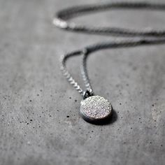 "A delicate 12mm (about 1/2\") round quartz druzy cabochon with a silvery gray titanium diffused coating set in a hand fabricated bezel of fine and sterling silver and oxidized for an organic, mysterious effect. The sterling silver cable chain necklace drapes a petite 18\" in length including the sterling lobster clasp. This necklace is made to order and will be sent out within 5 weeks. **The oxidation is not permanent, but will wear out uniquely with each owner like a pair of jeans.** All jewel Gray Round Jewelry For Gift, Gray Round Jewelry Gift, Gray Minimalist Jewelry For Everyday, Gray Minimalist Jewelry For Everyday Wear, Minimalist Gray Jewelry For Everyday, Minimalist Gray Sterling Silver Jewelry, Minimalist Round Oxidized Jewelry, Minimalist Necklaces With Oxidized Finish, Minimalist Necklace With Oxidized Finish