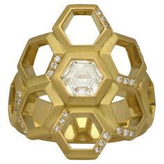 a gold ring with an octagonal cut diamond surrounded by smaller round and hexagonal diamonds