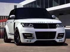 the white range rover is parked in front of a building with large windows and black rims