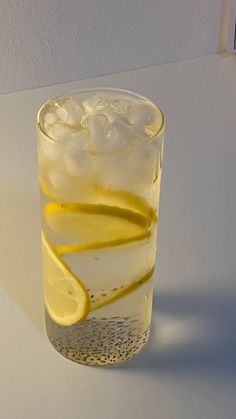 a glass filled with ice and lemon wedges on top of a white countertop