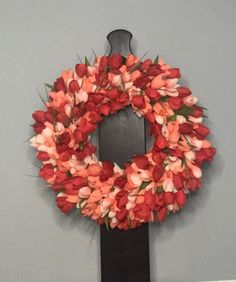 a red and white wreath hanging on the wall next to a black door with flowers in it