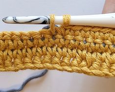 the crochet hook is being used to make a piece of yarn that has been woven