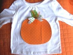 a white shirt with an orange pumpkin applique on the front and green polka dots on the back