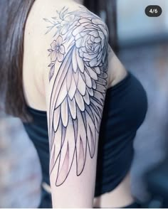 a woman's arm with an angel wing tattoo on her left shoulder and flowers in the center