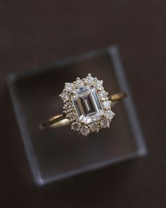 an engagement ring with a large emerald stone surrounded by small white and yellow diamonds on a black background