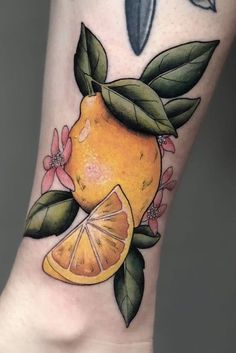 an orange with leaves and flowers on the side of her leg is featured in this tattoo