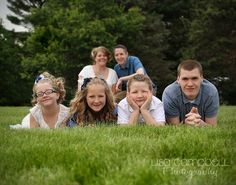 a group of people laying on top of a lush green field next to each other