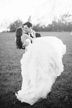 a bride and groom kissing in a field