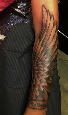 a person with a black and grey tattoo on their arm that has an angel wing