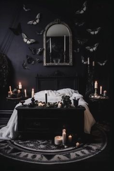 a bed with lots of candles on it in front of a mirror and butterflies flying around