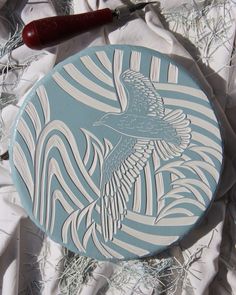 a blue and white plate sitting on top of a bed next to a red handled knife