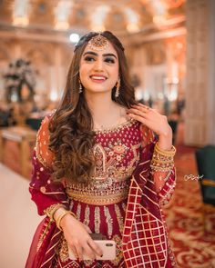 a woman in a red and gold outfit posing for the camera with her hand on her hip