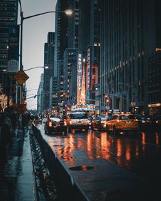 a city street filled with lots of traffic and tall buildings in the background at night